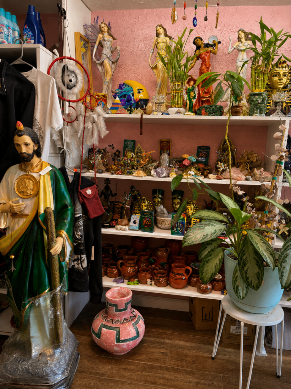 Rincón decorado con plantas, figuras y altar pequeño dentro del local