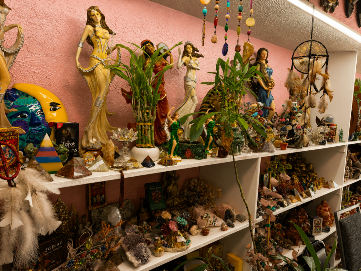 Estante con figuras espirituales, plantas y artesanías de devoción